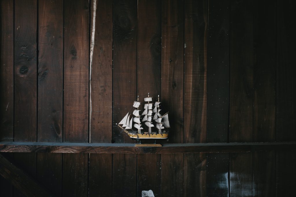 black, brown, and white galleon ship scale model on brown wooden shelf because someone took the time to build it