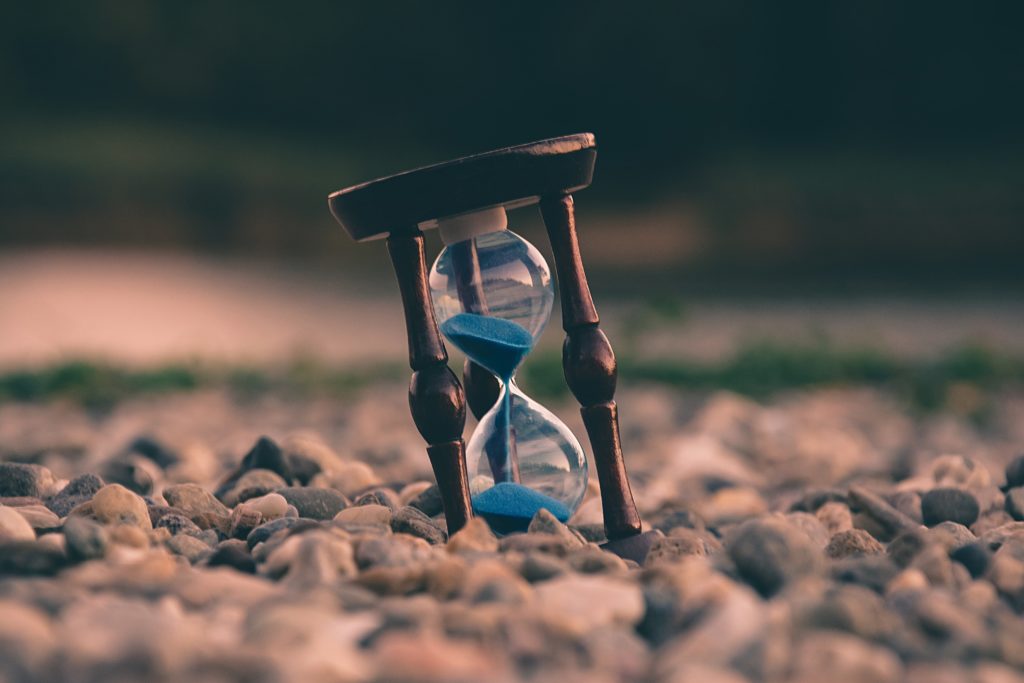 selective focus photo of brown and blue hourglass on stones representing how time can get away from you
