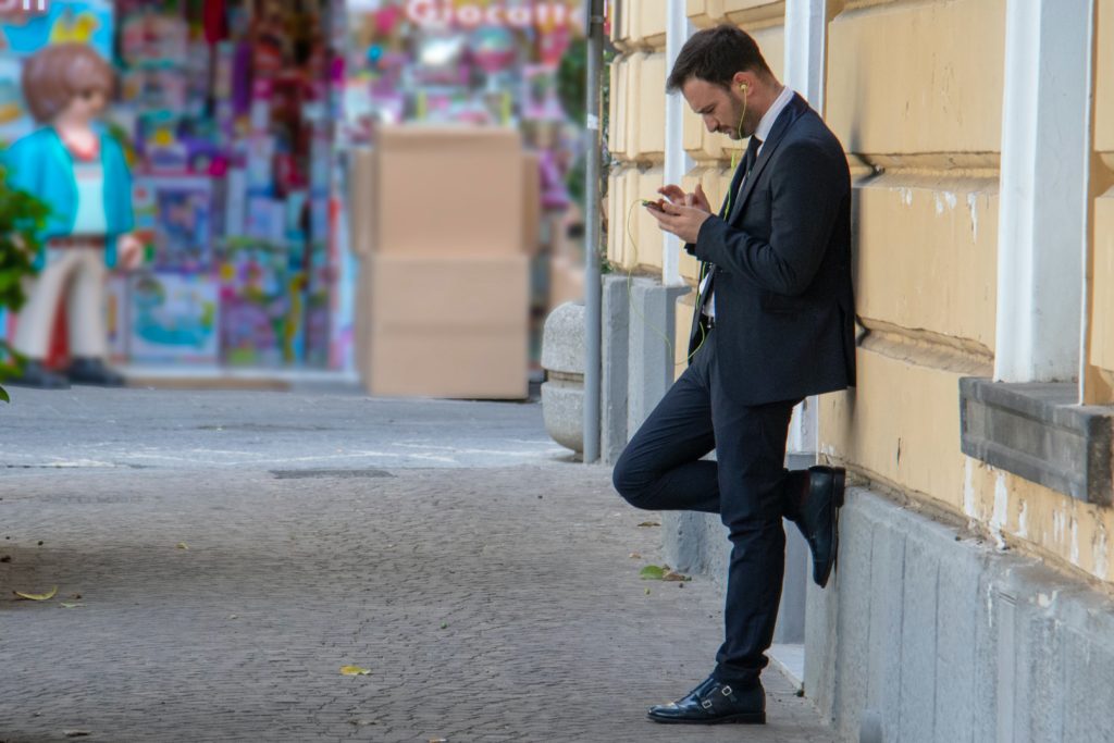 a man leaning against the wall texting someone from his past