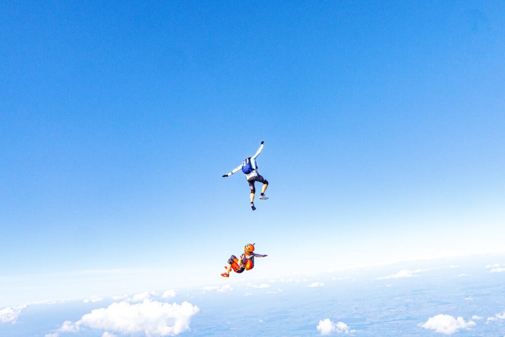 two people flying through the air on a pair of parachutes and this is dangerous with perceived knowledge of the risks