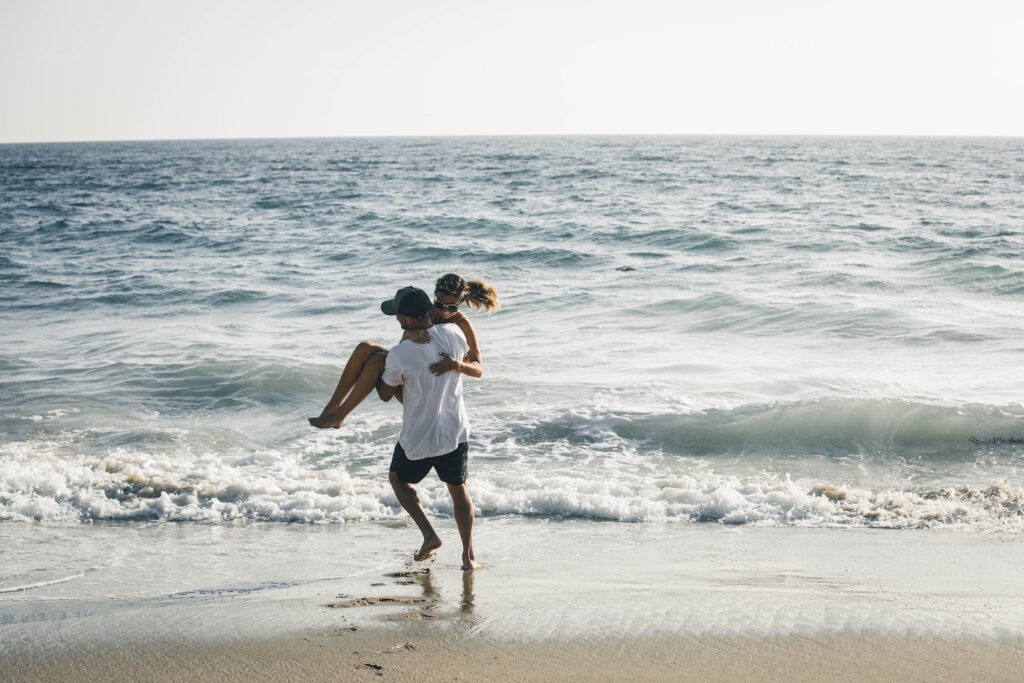 man carrying woman on seashore WOmen are drawns to men with a defined purpose.