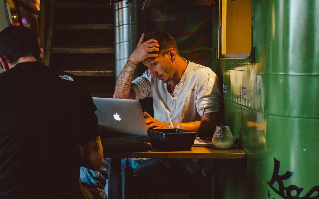 man in front of silver MacBook while scratching his head